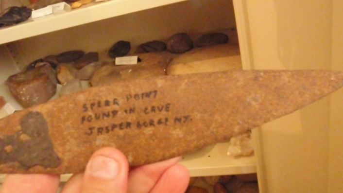 Rusted spear with museum writing on it, held in hand.